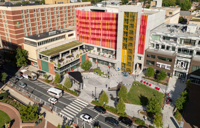 A view of Ewell Plaza highlights the dynamic, flexible ‘abstract rose’ design, integrating circulation and unifying spaces like Binns Park and Queen Street. New mixed-use development and the public library with an art façade further activate the plaza.