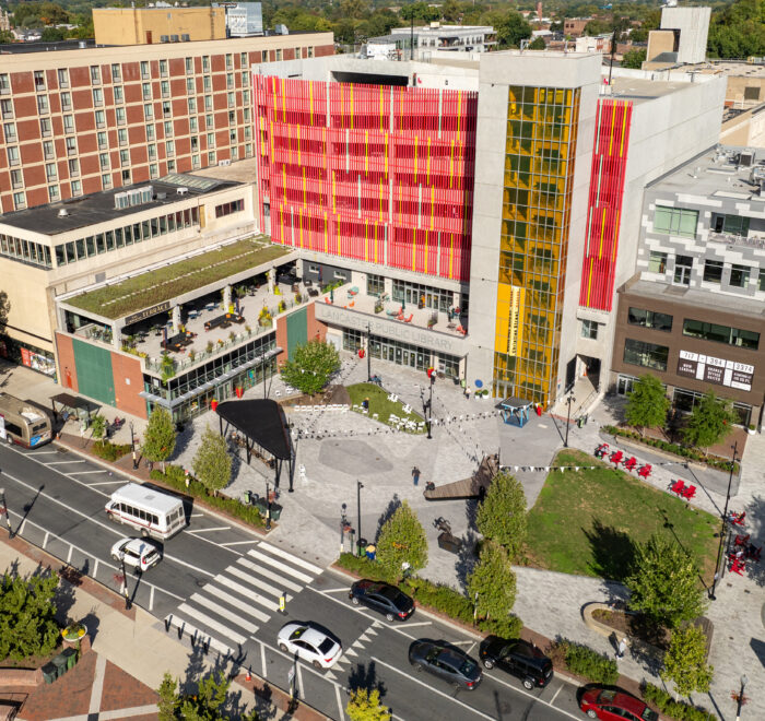 A view of Ewell Plaza highlights the dynamic, flexible ‘abstract rose’ design, integrating circulation and unifying spaces like Binns Park and Queen Street. New mixed-use development and the public library with an art façade further activate the plaza.