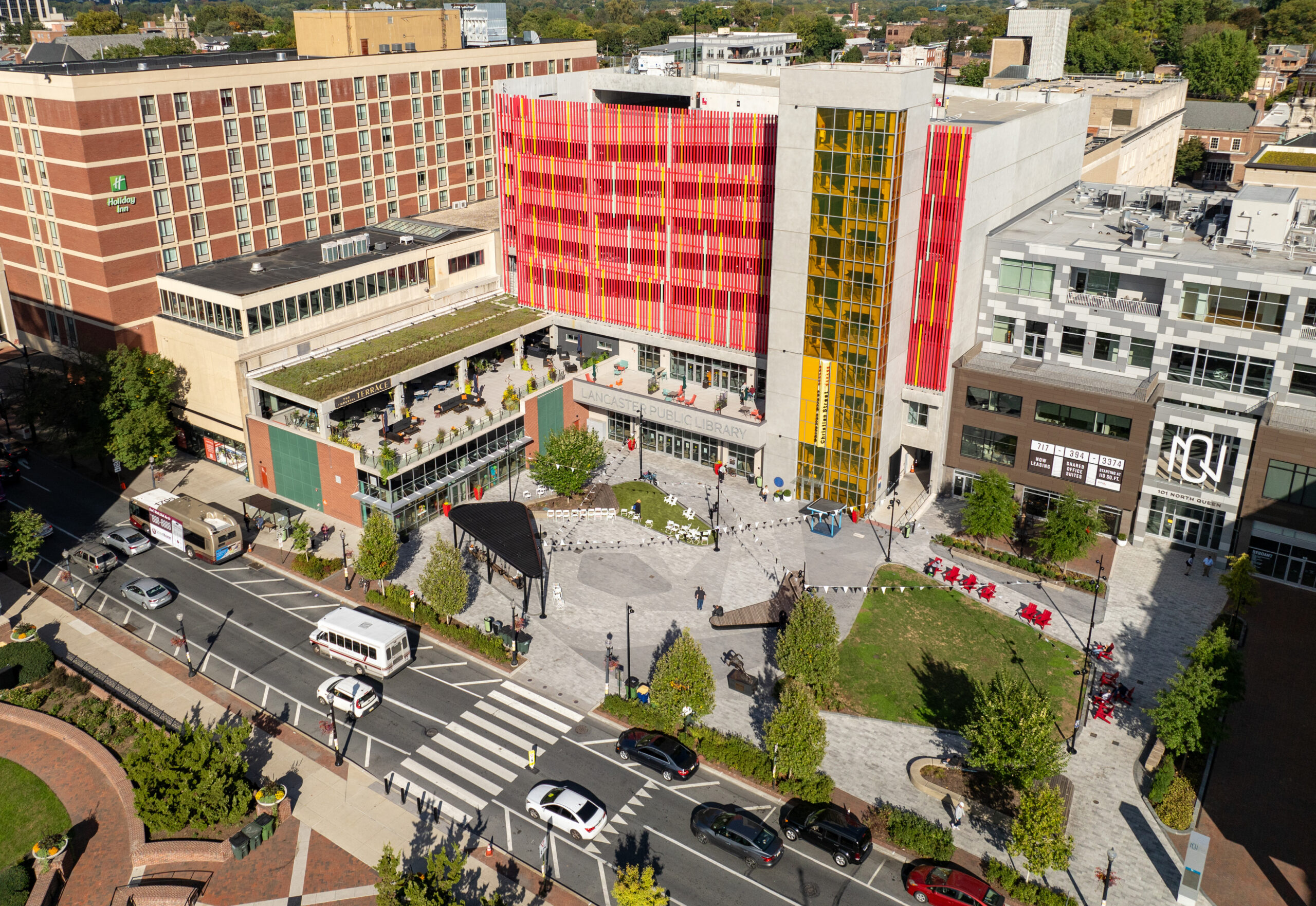 A view of Ewell Plaza highlights the dynamic, flexible ‘abstract rose’ design, integrating circulation and unifying spaces like Binns Park and Queen Street. New mixed-use development and the public library with an art façade further activate the plaza.
